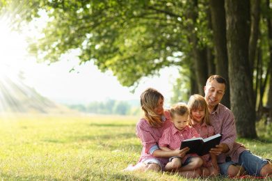 a Young family reading the Bible in nature